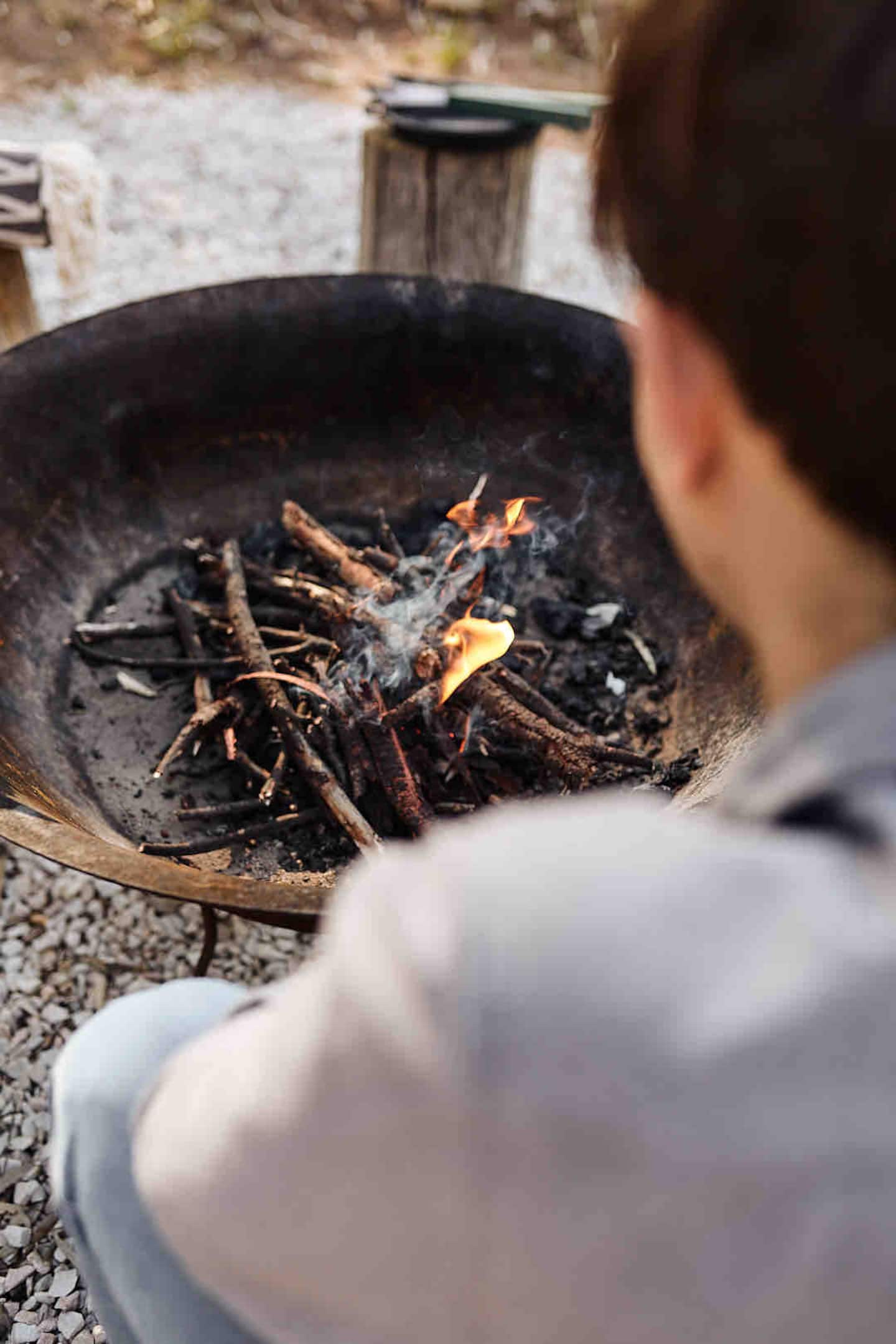 A guest tending a small fire in the outdoor firepit
